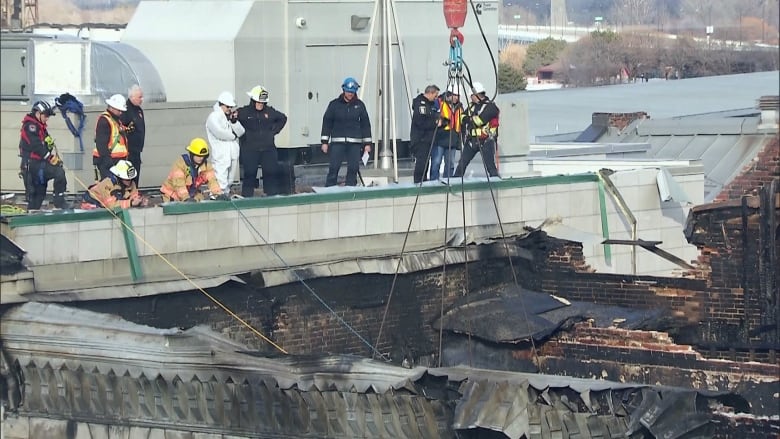 people standing on the edge of a burnt building looking down