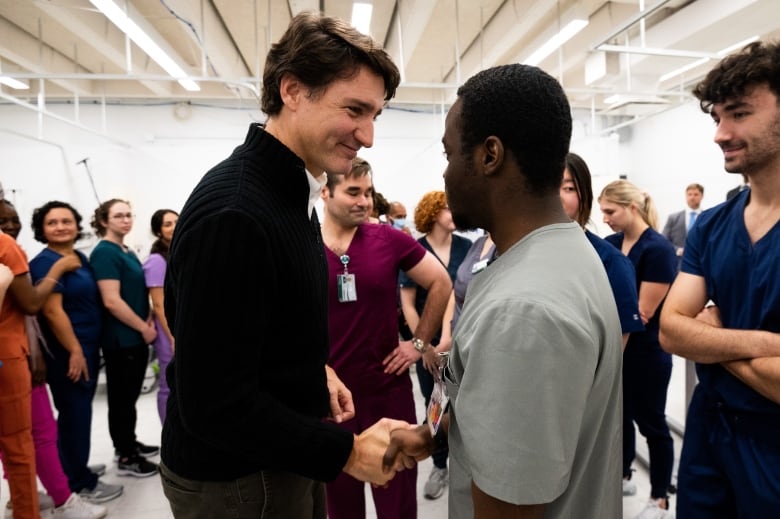 Justin Trudeau smiles as he shakes hand with a student in a room full of Algonquin College nursing students.