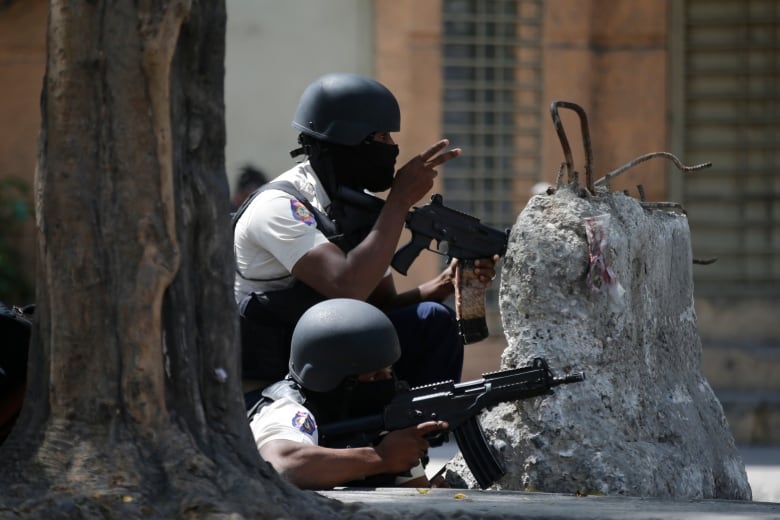 Police officers take cover during an anti-gang operation in the Lalue neighborhood of Port-au-Prince, Haiti on March 3, 2023.