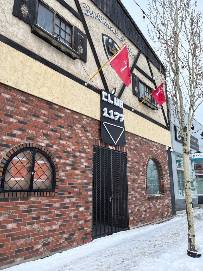 Closed nightclub doors in Prince George. Red and white flags of The United People of Canada flags are flying outside: a white tree on a red field.