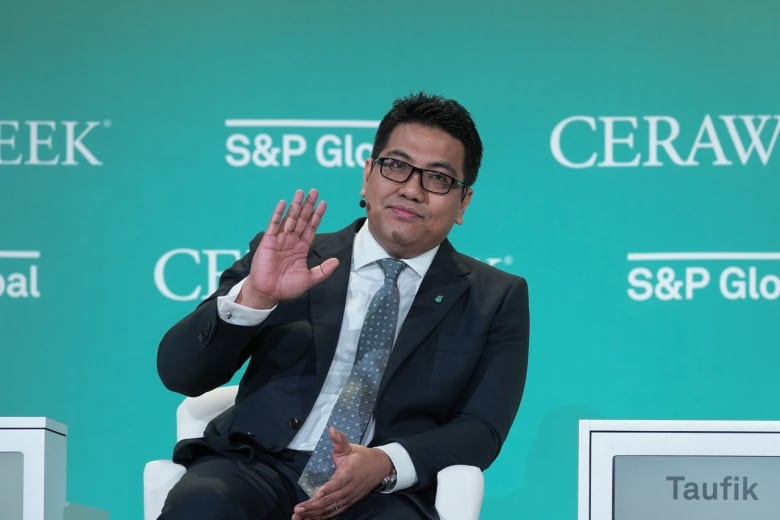 The chief executive of Petronas motions to the crowd while on stage at a conference.