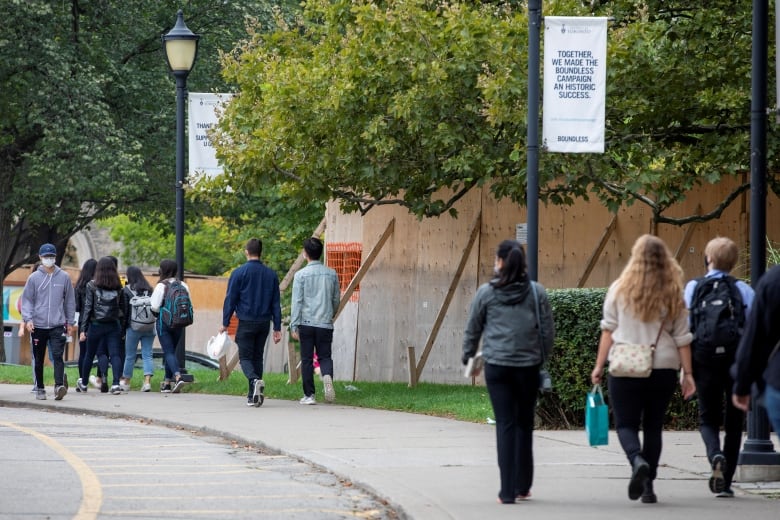 Students walk on a sidewalk at the University of Toronto.