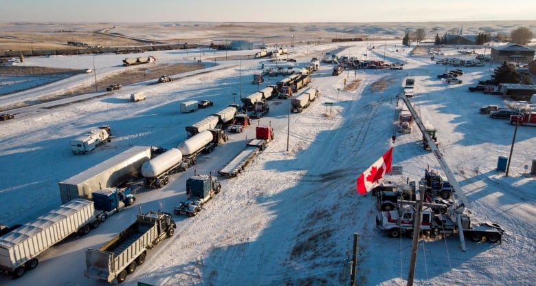 an aerial view of a line of trucks parked on a snowy road