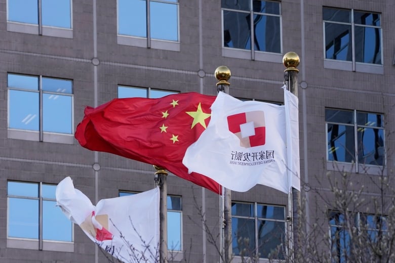 Three flags fly outside an office building, including on Chinese national flag and two white flags bearing the logo of the China Development Bank.