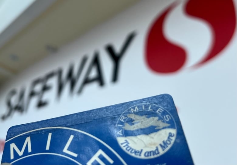 An Air Miles card from the late 1990s is pictured in front of a modern Safeway sign, which is slightly blurred.
