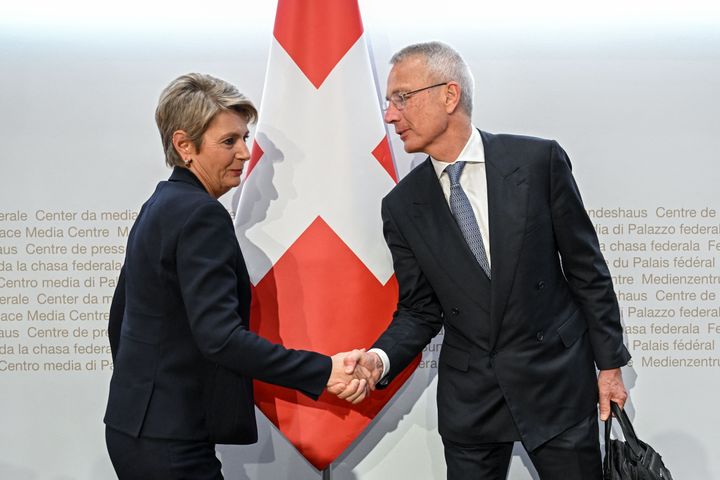 Swiss Finance Minister Karin Keller-Sutter (L) shakes hands with Credit Suisse chairman Axel Lehmann at the end of a press conference over the buyout on Sunday
