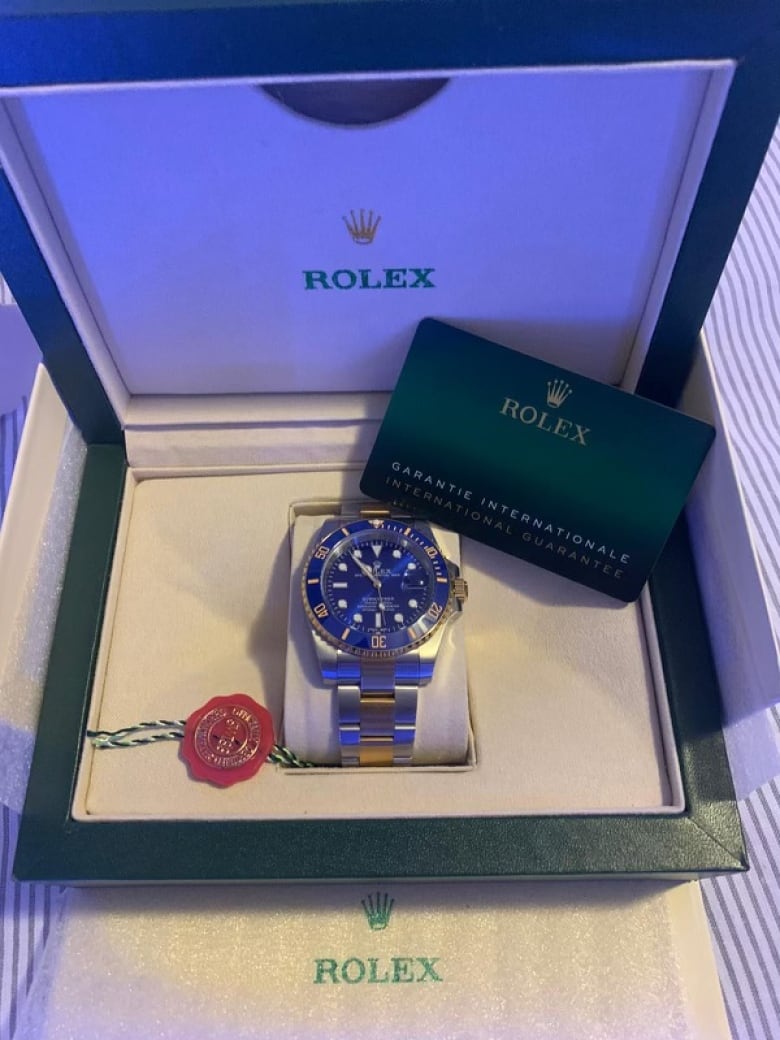 A gold and blue Rolex submariner watch sits in a box.