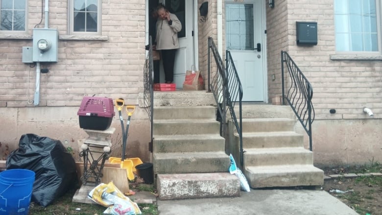 A woman on the phone is at the entry way to a house