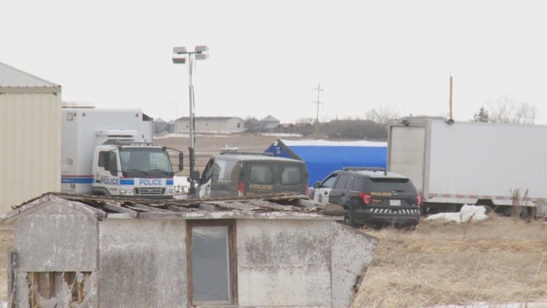 Multiple police vehicles and a blue tent are pictured.