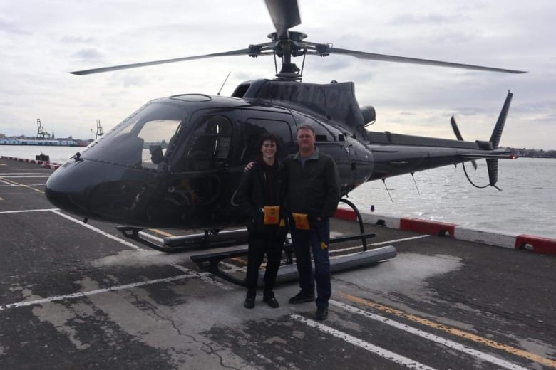 Harrison and his father Trevor stand in front of helicopter. 