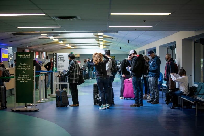 A line forms to rent cars inside an airport.