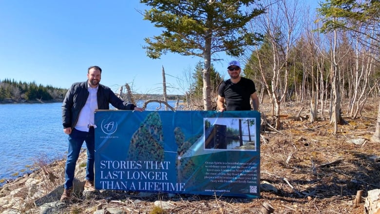 Two men in the woods hold a sign that says "Stories that will last longer than a lifetime."