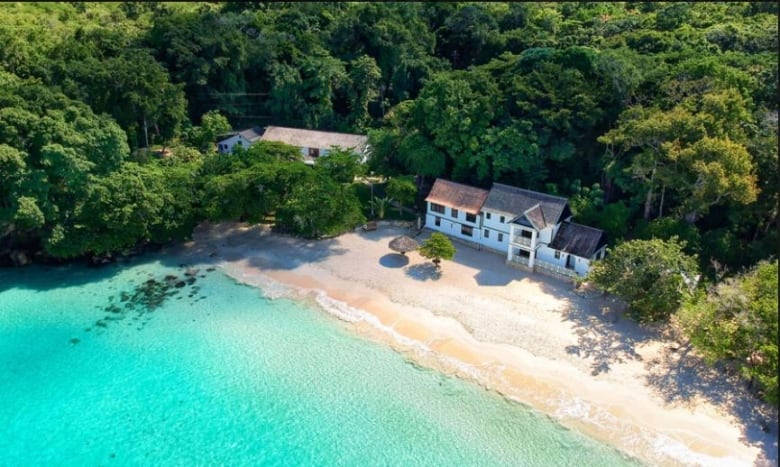 An image of a house on the ocean taken from a drone