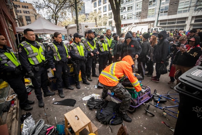 VPD officers form a line to push back protesters and advocates while city employees work to dismantle tents along East Hastings in the downtown Eastside neighbourhood of Vancouver, British Columbia on Wednesday, April 5, 2023. 