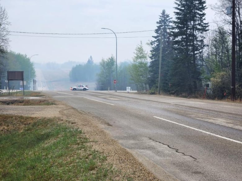 View of a long road with a police car and smoke in the distance