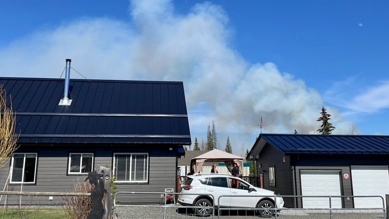 Plumes of smoke rise from behind two rural properties.