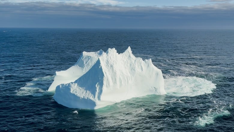 An aerial photo of an iceberg in the ocean.