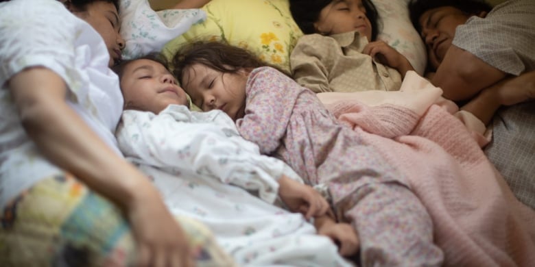 Several children lie together in a bed.