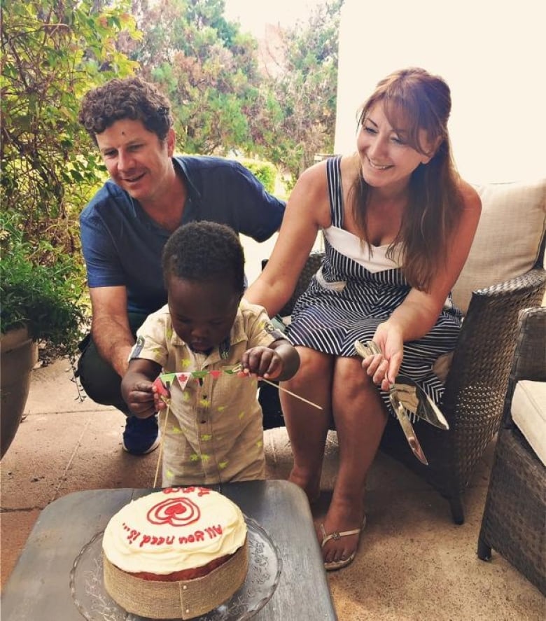 A man and a woman seen with a little boy and a cake.