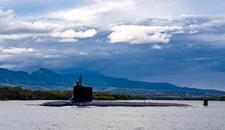 A nuclear submarine travels on the surface as it leaves harbour.