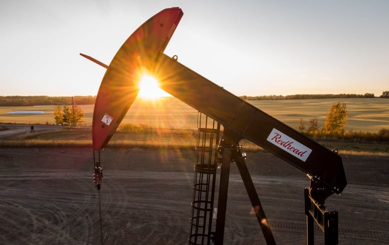 A pumpjack extracts oil as the sun sets. 