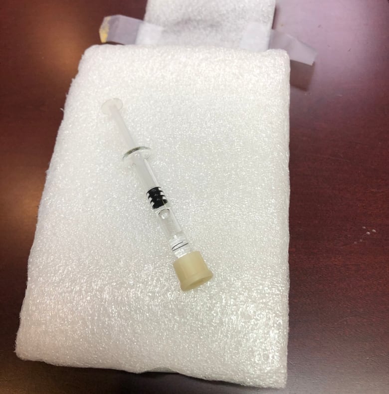 A syringe lies on a white cloth.
