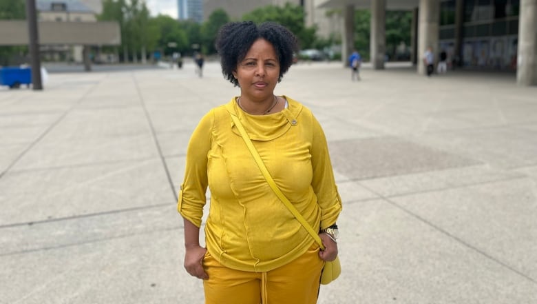 A woman stands in the plaza in front of Toronto's city hall.