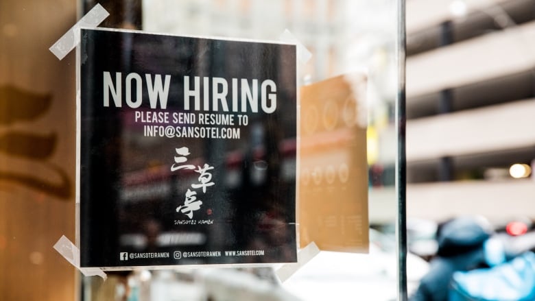 A Now Hiring sign outside a restaurant.