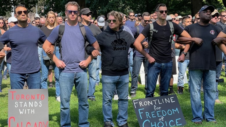 Men with anti-vaxx slogans on signs linking arms