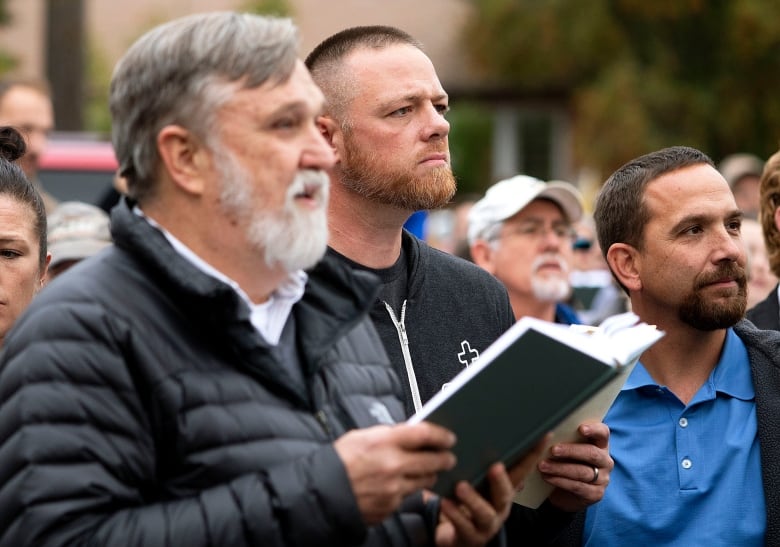 Christ Church Pastor Doug Wilson, center, and Latah County Commission candidate Gabriel Rench, center, sing a hymn over the noise from counter-protesters playing drums during "psalm sing" on Friday, Sept. 25, 2020, outside city hall in Moscow, Idaho. Church members were protesting against a city public-health order that requires people to either socially distance or wear a face mask in public. Rench was arrested for violating the public-health order at a similar event on Wednesday.(Geoff Crimmins/The Moscow-Pullman Daily News via AP)