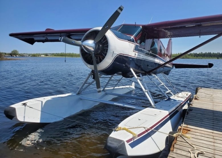 A float plane sits at a dock on a lake.