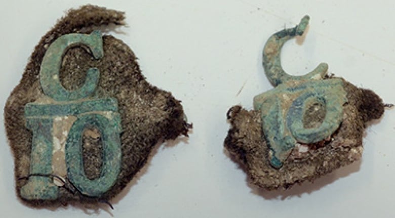Portions of a collar with a large tarnished 'C' over a '10'. 