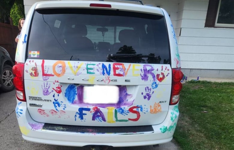 A van decorated with colourful handprints in rainbow colours. 