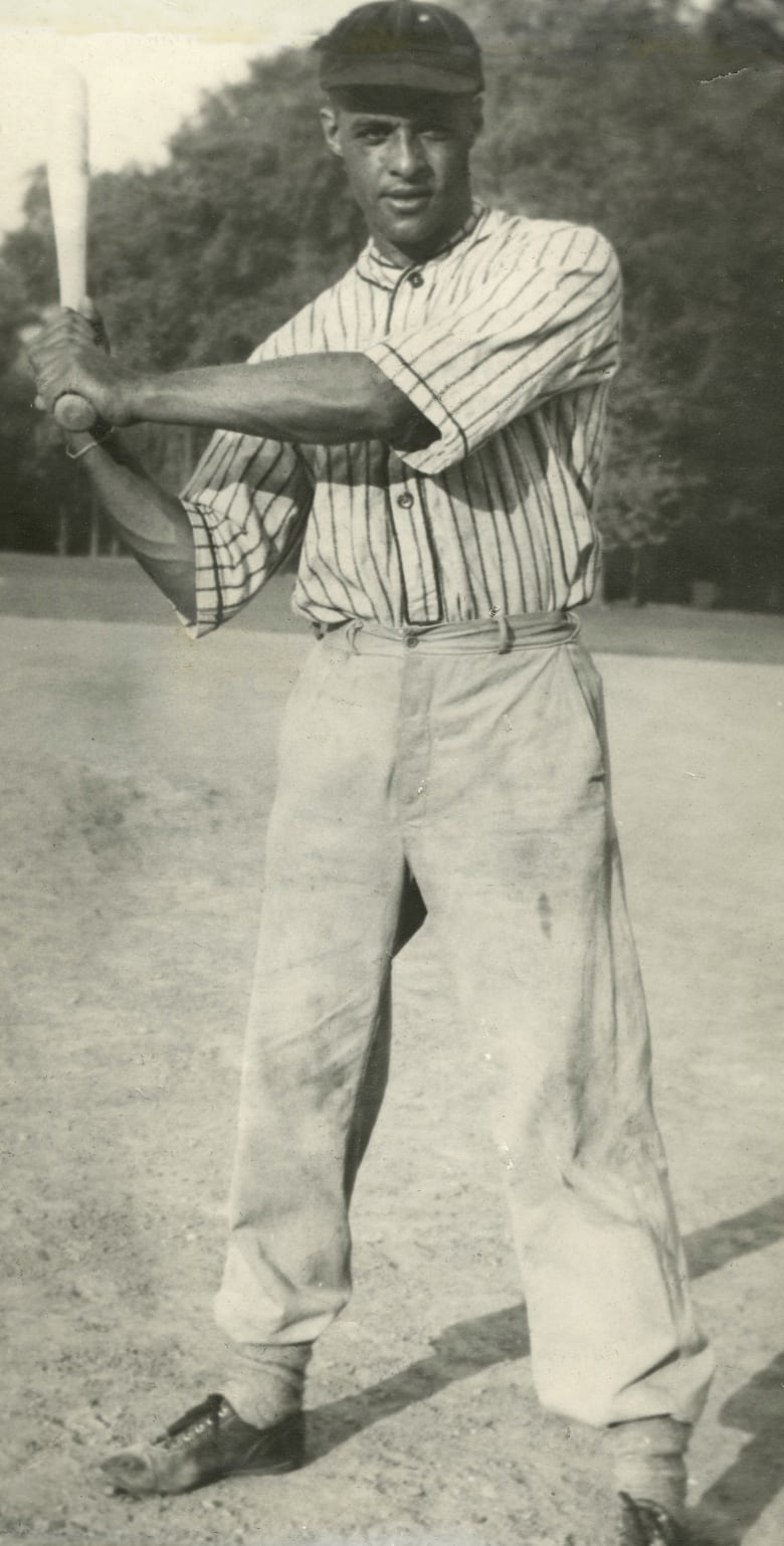 A black and white photograph of a man in full baseball attire.