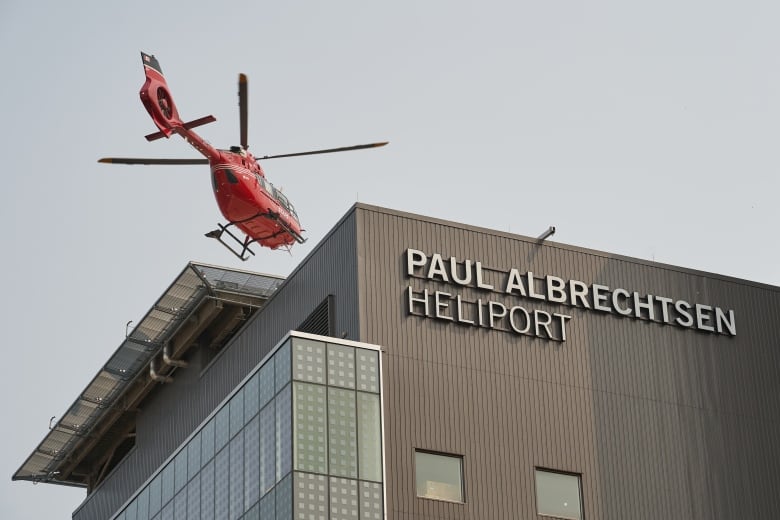 A helicopter lands on a helipad atop a hospital.