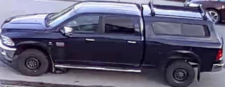 A surveillance shot of a blue pickup truck with a covered rear.