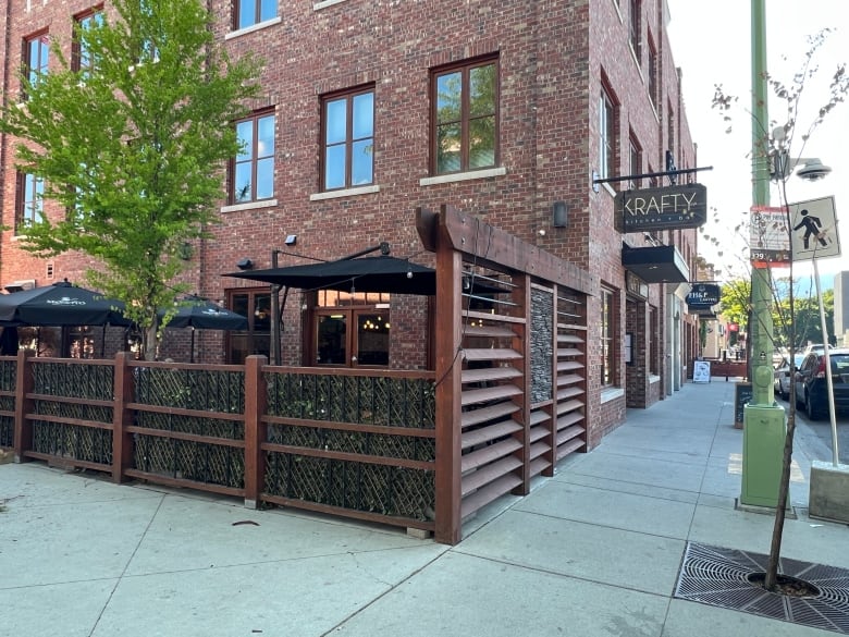 An outdoor patio next to a brick building with a sign reading 'Krafty Kitchen + Bar'.