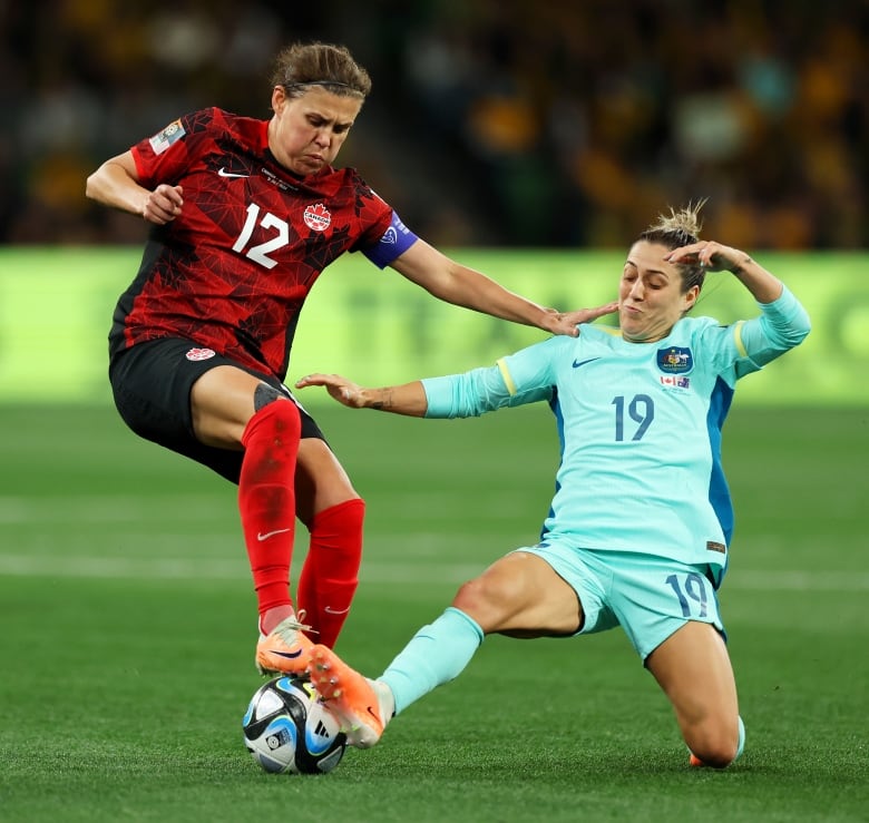 Two women soccer players battle for the ball.