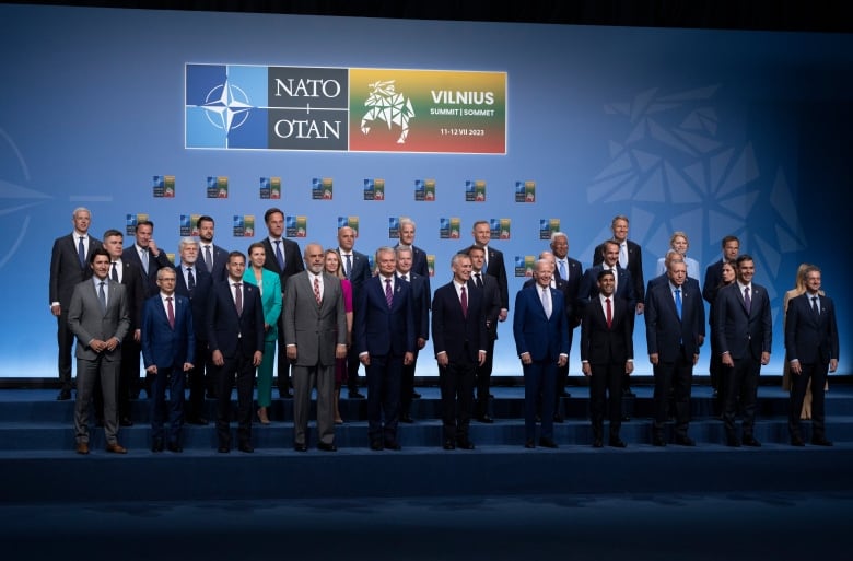 The heads of government of NATO countries pose for a photo on a stage in Lithuania. 
