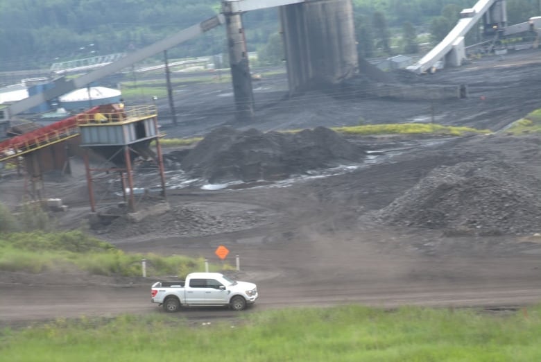 A white pickup truck drives through a coal mine. 