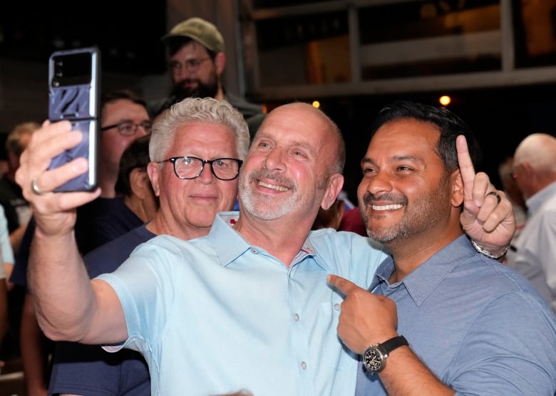 Three men are taking a selfie and smiling.