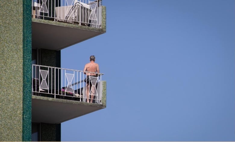 A man stands on his balcony in Vancouver during the July 2021 heat wave.