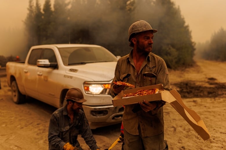 Firefighters from an Alaska smoke jumpers unit refuel with pizza on the fire line of a wildfire burning near a highway in northern British Columbia, Canada on July 11, 2023. 