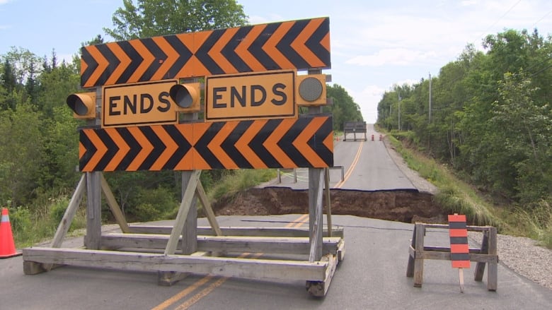 An orange sign that says ends in front of a road that has washed away.
