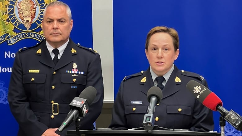 A man and woman in RCMP uniform speak at a news conference.