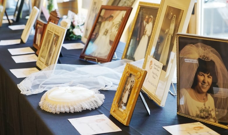 Wedding photos, a white pillow and a veil on display on a table