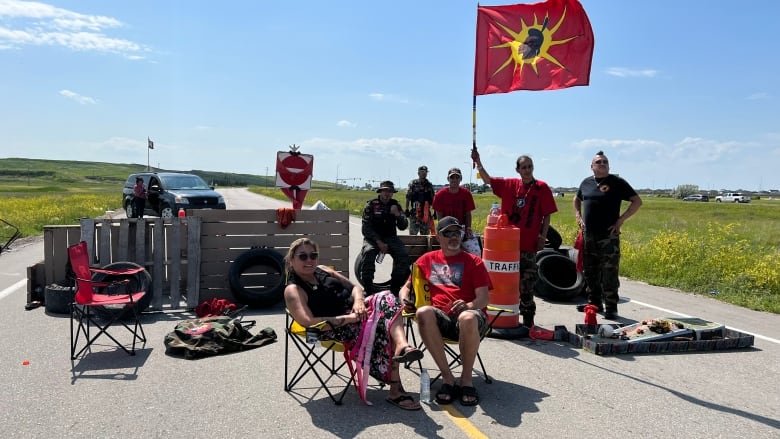 A group of seven protestors block a road leading to a landfill. 