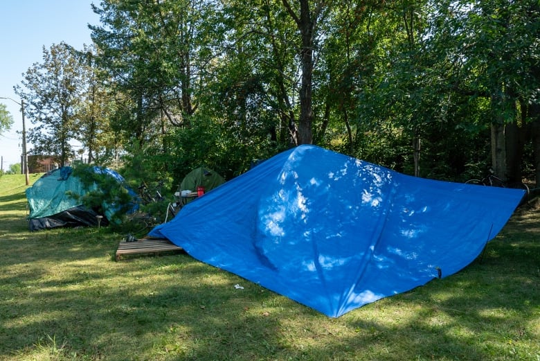 A blue tarp covers a cluster of tents outside.