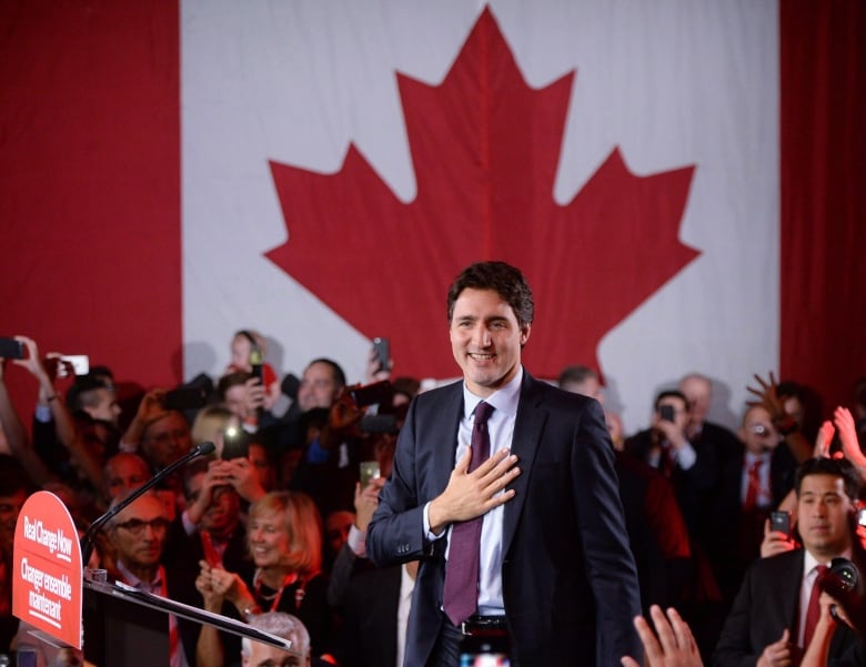 A man stands at a podium in front of a Canadian flag.