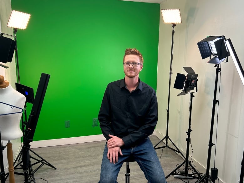 Adam Stratychuk sitting in front of a green screen on a stool